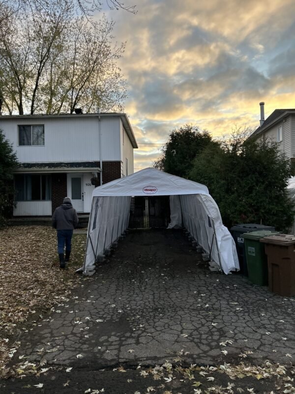Abri d'auto simple installé dans une entrée étroite, le long de la maison