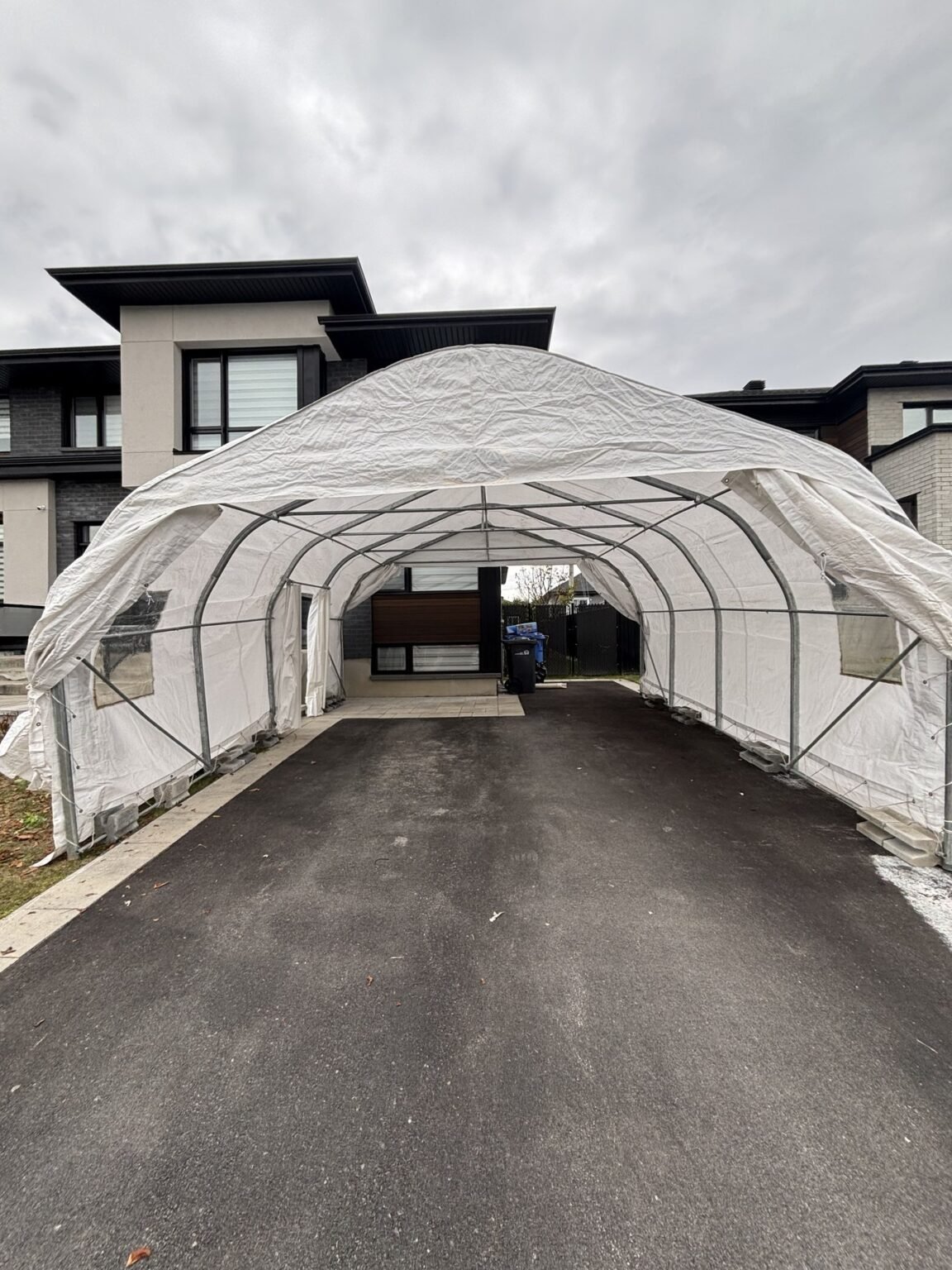 Abri d'auto double à toit arrondi installé devant une maison moderne