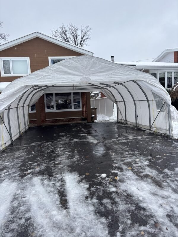 Abri d'auto double installé devant un bungalow en brique, entrée enneigée
